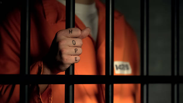 Hope word on imprisoned man fingers, holding jail bars, dream about freedom Hope word on imprisoned man fingers, holding jail bars, dream about freedom sentencing stock pictures, royalty-free photos & images