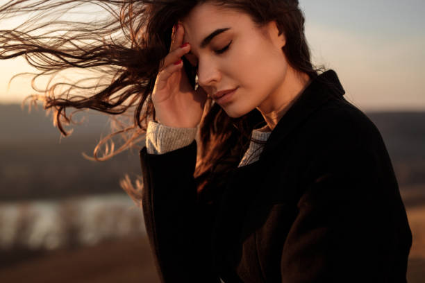 Hopeless sad young female in autumn nature Side view of exhausted lonely young female with long hair fluttering in wind having problems and thinking about life in autumn evening in nature obsession with failure stock pictures, royalty-free photos & images