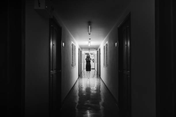 Horror photo of woman with long hair walking on corridor in white tone stock photo
