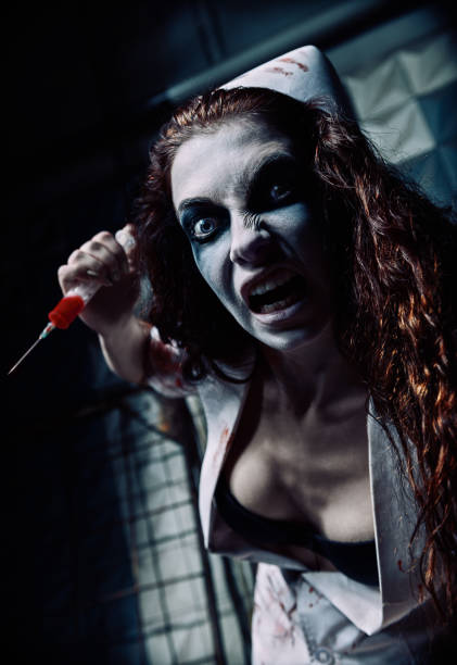 Horror shot: crazy evil nurse (doctor) with bloody syringe in hand. Zombie woman (living dead). Monster from nightmare stock photo