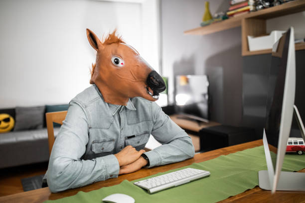Horseman with horse mask working at home office Business man with horse mask working at home office horse mask photos stock pictures, royalty-free photos & images