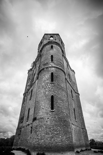 A medieval stone tower stands abandoned in a rural setting
