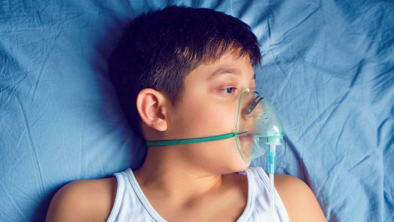 Hospital emergency room, Kid with oxygen mask on the blue bed.