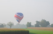 istock Hot air balloon flying over farmland 1351358630