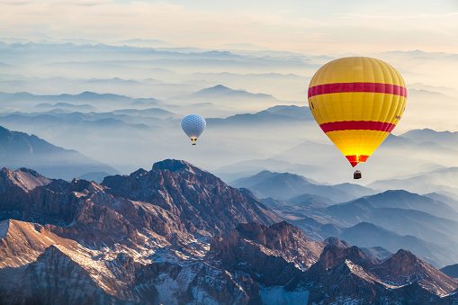 Hot air balloon flying over fogy mountains