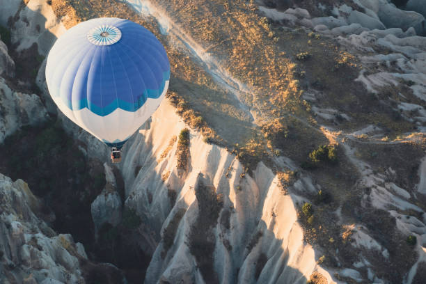 hot air balloon with blue and white colors pattern rising over the Cappadocian valley stock photo