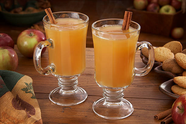 Hot Apple Cider for two Steaming hot apple cider on a table with apples and ginger cookies. cider stock pictures, royalty-free photos & images