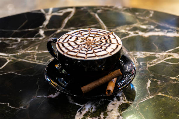 Hot Cappuccino coffee with zigzag caramel motif or spiderweb art floating on top and coffee beans. Coffee break at retro style coffee shop. stock photo
