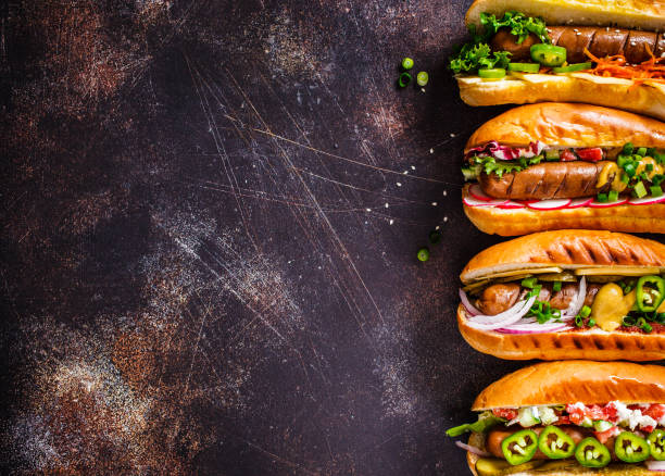Hot dogs with different toppings on dark background, copy space, top view. Fast food concept. Hot dogs with different toppings on a dark background. Fast food concept. sausage photos stock pictures, royalty-free photos & images
