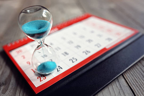 Hourglass on calendar Hour glass on calendar concept for time slipping away for important appointment date, schedule and deadline deadline stock pictures, royalty-free photos & images