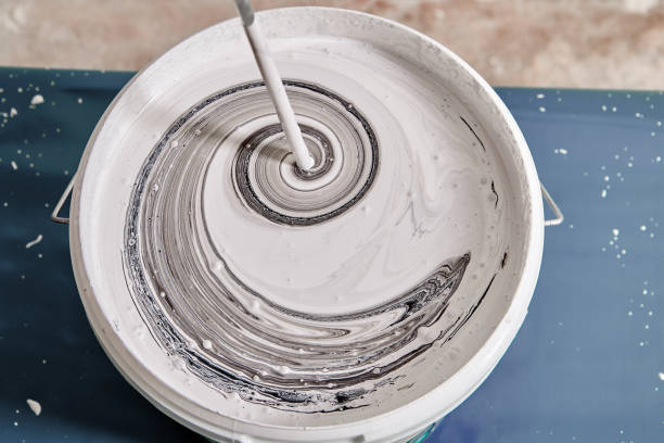 house painter makes gray color while mixes black and white using painting mixer. - misturar imagens e fotografias de stock