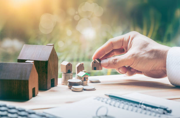 House placed on coins Men's hand is planning savings money of coins to buy a home concept concept for property ladder, mortgage and real estate investment. for saving or investment for a house, stock photo