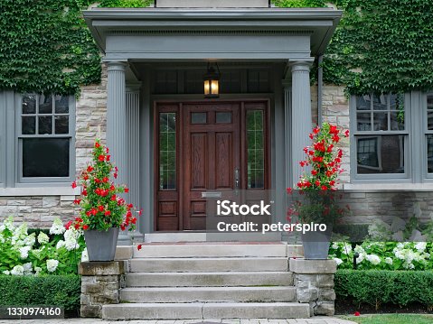 istock House with elegant wood grain door, surrounded by ivy and  red amaryllis and white hydrangea flowers 1330974160