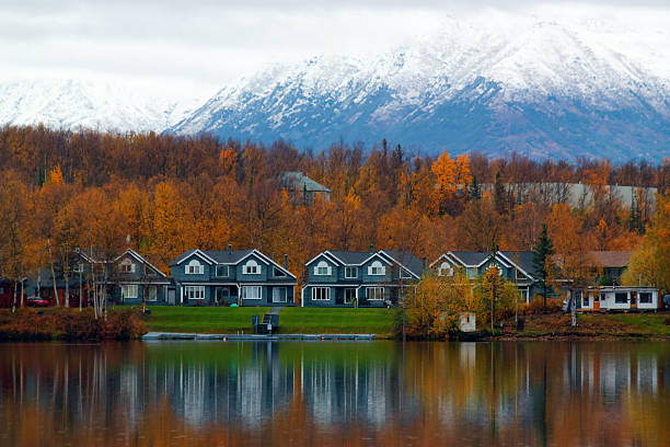 Houses on shore of lake in Wasilla Houses on shore of lake in Wasilla (AK, USA) with orange trees and high mountain in autumn alaska stock pictures, royalty-free photos & images