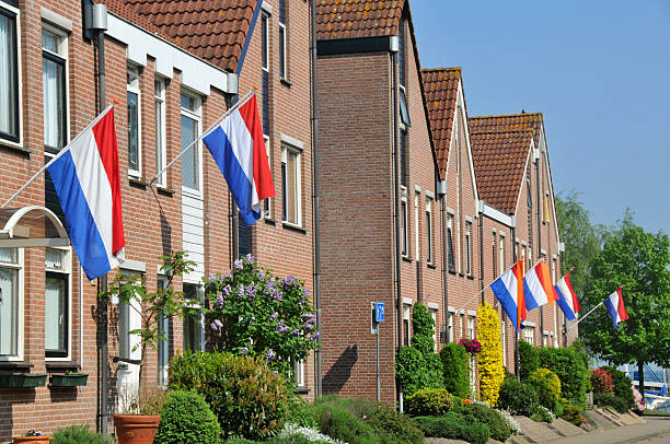 häuser mit niederländischer flagge an einem sonnigen tag - holländische flagge stock-fotos und bilder