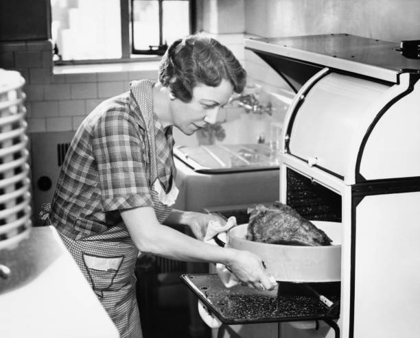 Housewife removing turkey from oven, (B&W)  housewife stock pictures, royalty-free photos & images