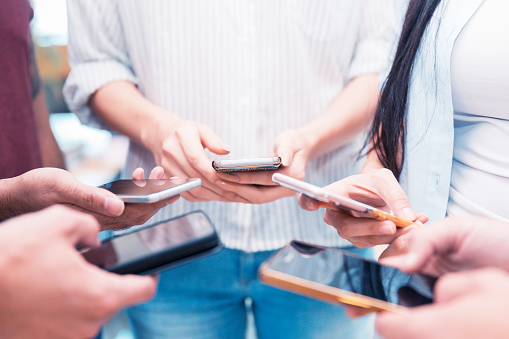 Group of people holding their smartphone and testing a mobile app.