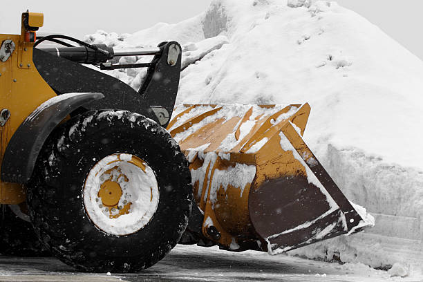 huge snow plow plowing in parking lot after storm stock photo