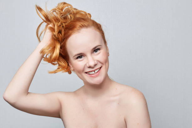 Human face expressions, emotions and feelings Human face expressions, emotions and feelings. Closeup studio portrait of beautiful young cheerful Caucasian redhead freckled woman smiling playfully at the camera demonstrating something on grey wall with copy advertising space. teen redhead nude stock pictures, royalty-free photos & images