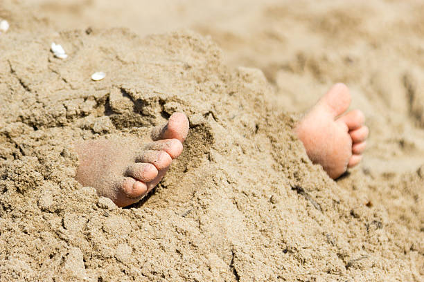 Human feet buried in sand. Summer beach. Human feet buried in beach sand. Summer holidays fun at sea. human feet buried in sand. summer beach stock pictures, royalty-free photos & images