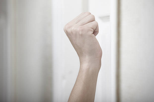Human fist hovering in front of door, getting ready to knock stock photo