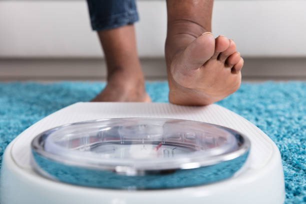 Human Foot Stepping On Weighing Scale Close-up Of A Human Foot Stepping On Weighing Scale feet unit of measurement stock pictures, royalty-free photos & images