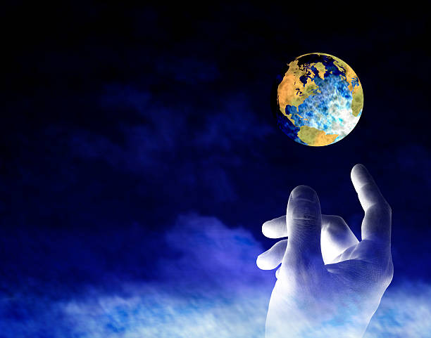 Human hand reaching towards the earth symbolizing creation stock photo