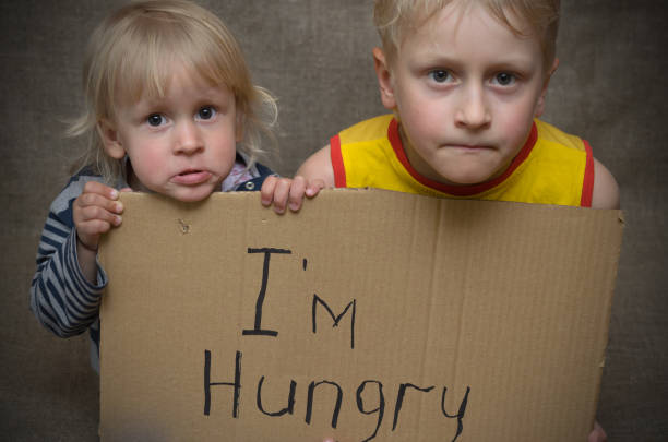 A hungry boy and a girl with a cardboard tablet with the inscription I'm hungry . A hungry boy and a girl with a cardboard tablet with the inscription I'm hungry . hungry child stock pictures, royalty-free photos & images