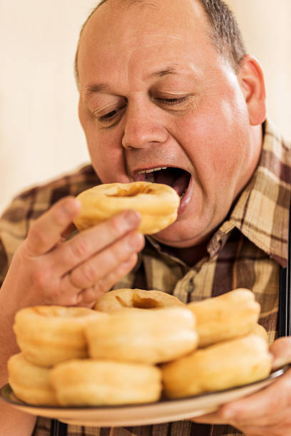 Hungry overweight man eating donuts. stock photo.