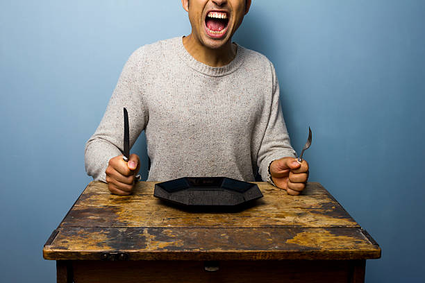 Hungry young man is screaming for his dinner stock photo