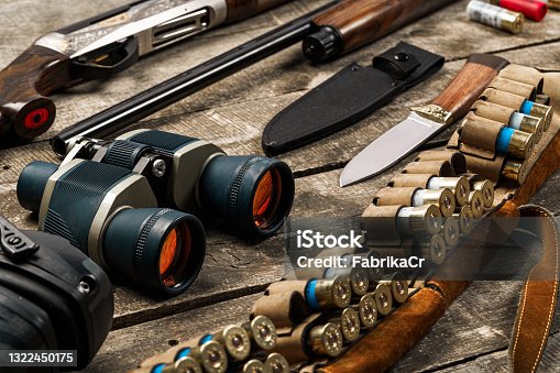 istock Hunting equipment on old wooden background including rifle, knife, binoculars and cartridges 1322450175
