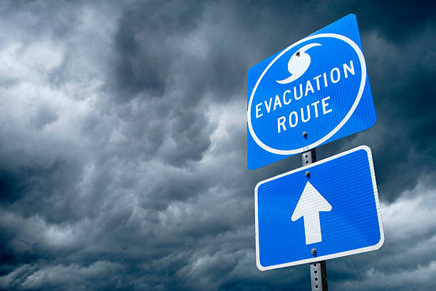 Hurricane Evacuation Route Road Sign A Directional Sign in Front of Storm Clouds indicating the Storm Evacuation Route. evacuation stock pictures, royalty-free photos & images