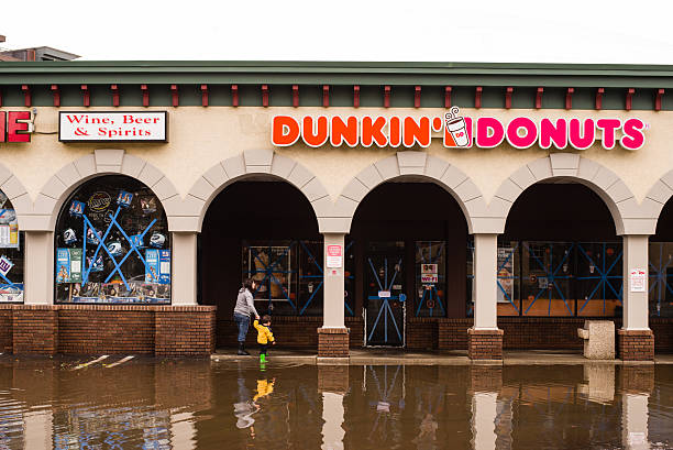 Hurricane Sandy: women and child on a flooded street "Hoboken, New Jersey, USA - October 31, 2012: Women and a child walking on a flooded street approaching abandoned Dunkin Donuts entrance after Hurricance Sandy landfall" new jersey street flooding stock pictures, royalty-free photos & images