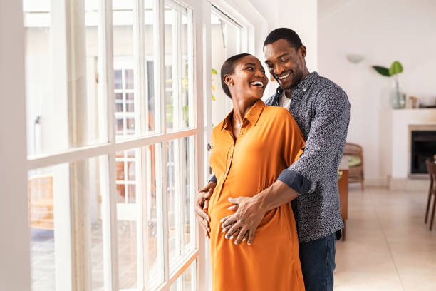 Husband embracing pregnant woman from behind stock photo