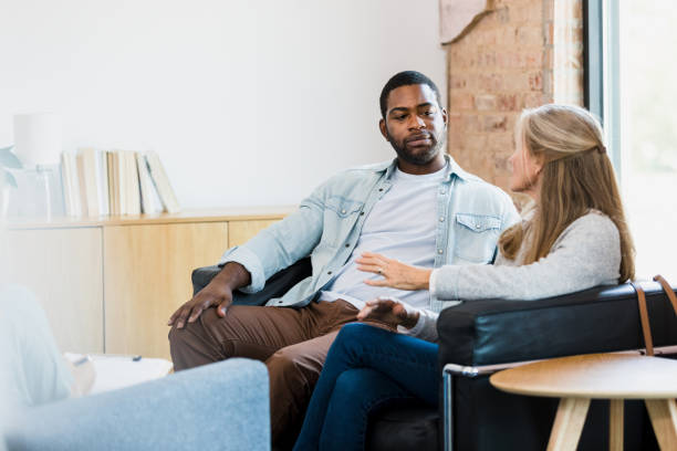 Husband listens as wife shares during counseling session stock photo