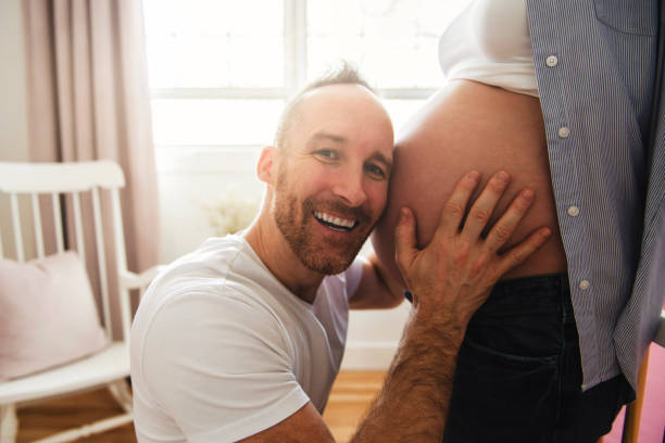 echtgenoot op de babyruimte thuis met zwangere vrouwenbuik - wiegman stockfoto's en -beelden