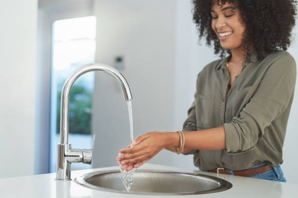 Shot of a young woman washing her hands at a round kitchen sink 