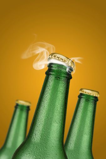 Green cold beer bottle with water drops and golden cap open on orange background.  high resolution, high post-production quality.