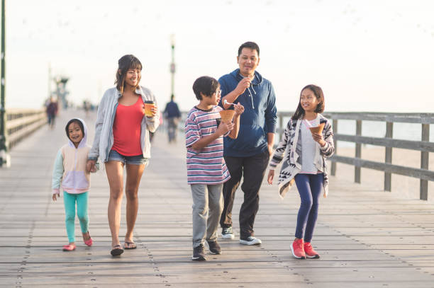 Ice cream on the boardwalk! An attractive Filipino couple and their three children eat ice cream cones as they walk down a California boardwalk by the beach boardwalk stock pictures, royalty-free photos & images