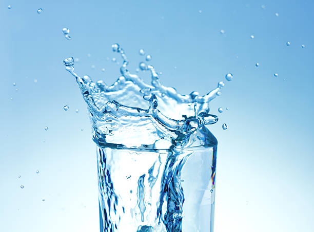 Ice cubes splashing into glass of water stock photo