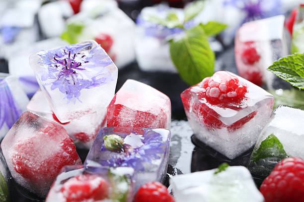 Ice cubes with raspberries and mint leaf on wooden table stock photo