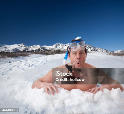 A senior man try's his luck at ice fishing by diving in the water. A comical view of life, and high adventure lifestyles or extreme sports.