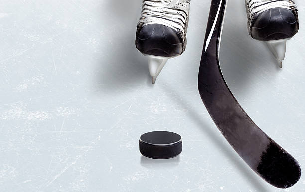 Ice Hockey Game With Copy Space Ice hockey game showing stick on puck with part of player's skates on ice and copy space. hockey stick stock pictures, royalty-free photos & images