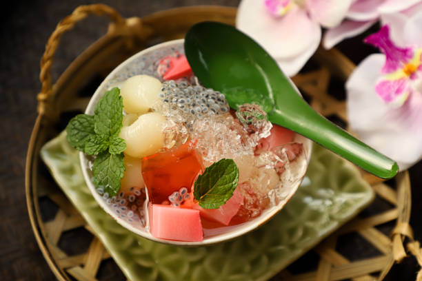Ice Longan Jelly, Icy Dessert of Jelly Cubes with Preserved Longan in Its Syrup Ice Longan Jelly, an icy dessert of strawberry milk agar and strawberry jelly cubes with preserved longan fruits with its syrup. Some crushed ice and basil seeds are added to the dish; then garnished with mint leaves. fruit ice stock pictures, royalty-free photos & images