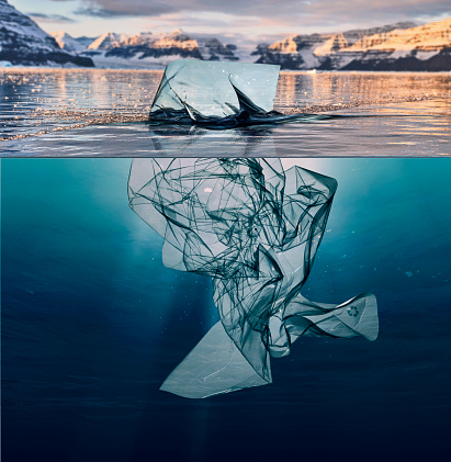 iceberg of garbage plastic floating in ocean with greenland background