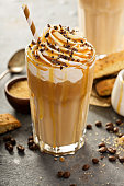 Iced caramel latte coffee in a tall glass with syrup and whipped cream