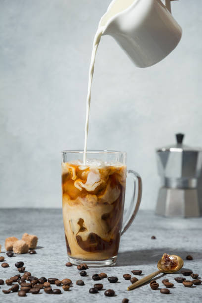 Iced latte coffee in cup glass with pouring milk Iced latte coffee in cup glass with pouring milk on grey pouring stock pictures, royalty-free photos & images