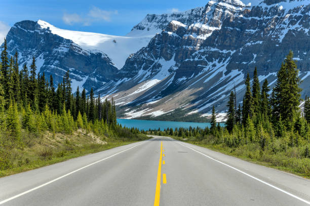 Icefields Parkway at Bow Lake - A Spring evening view of Icefields Parkway extending towards Bow Lake, with BowCrow Peak, Crowfoot Glacier and Crowfoot Mountain rising high behind, Banff National Park, AB, Canada. stock photo