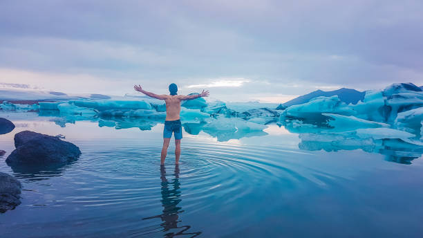 ijsland-man staande in de gletsjerlagune - ice swimming stockfoto's en -beelden