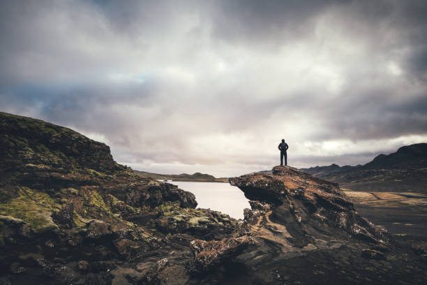 Icelandic Wilderness Man standing on the rock and enjoying the view on lake Kleifarvatn on the Reykjanes Peninsula in Iceland. extreme terrain stock pictures, royalty-free photos & images